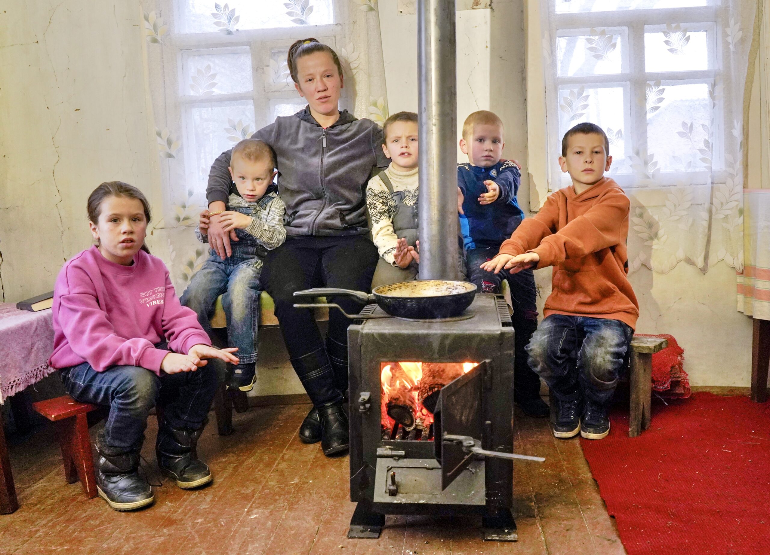 family getting warm around a wood-burning stove