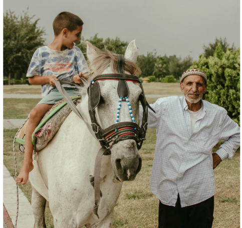 Young boy on white horse next to a man