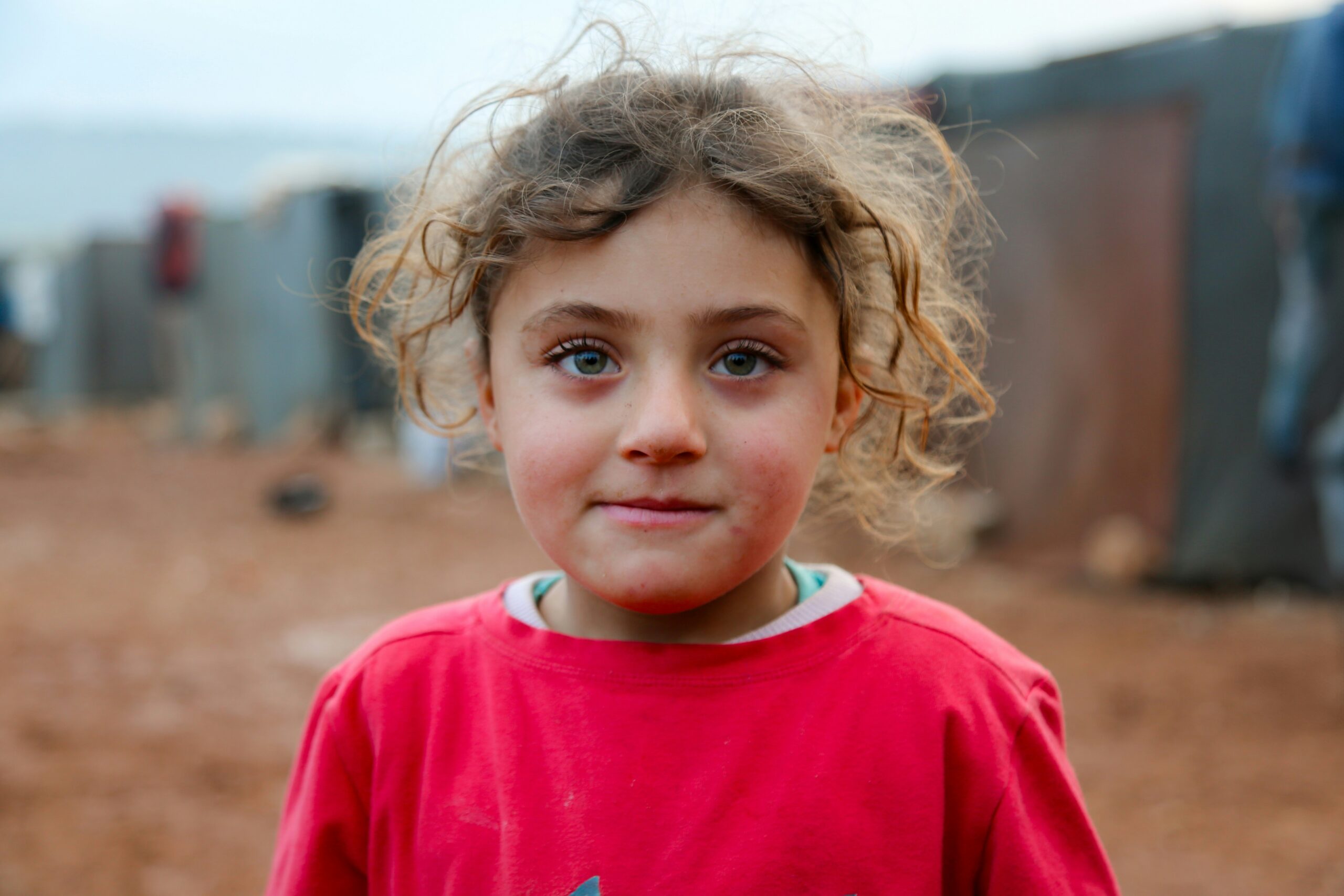 Close-up portrait of a young girl with curly hair, representing children at high risk of human trafficking and exploitation due to orphanhood.