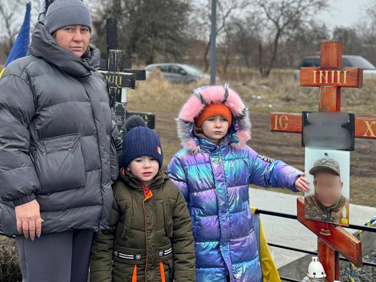 A women with three young children next to a memorial marker for al loved one.