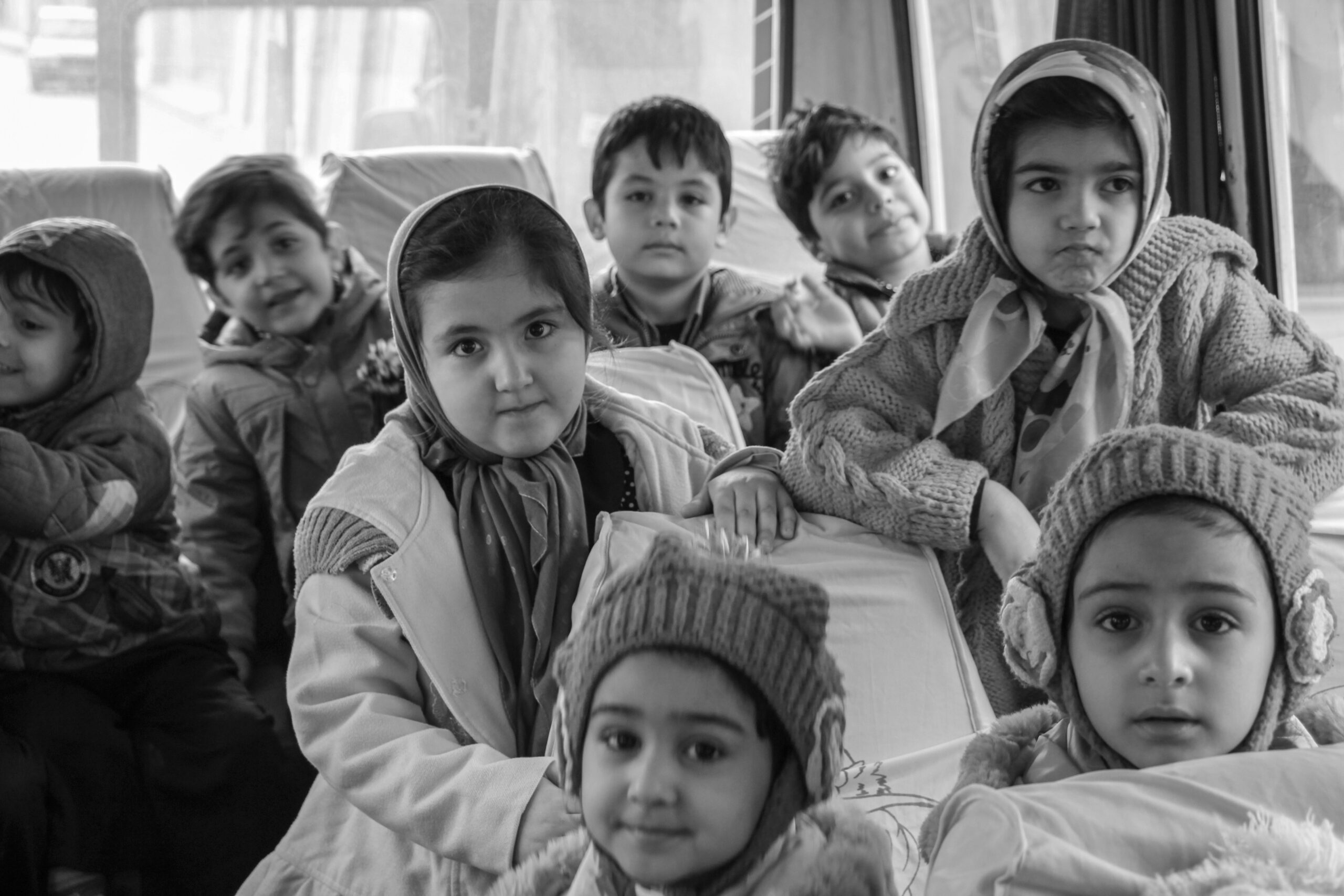 A group of children sitting together in a row, representing the shared experiences and trauma-attachment challenges of orphans.
