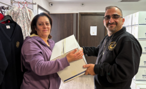 A man smiling while handing a large box of relief groceries to a woman in Nazareth.