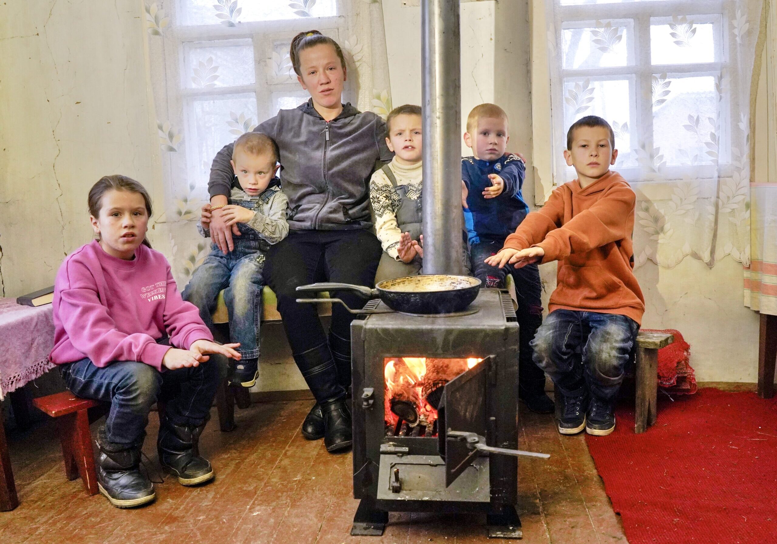 family getting warm around a wood-burning stove