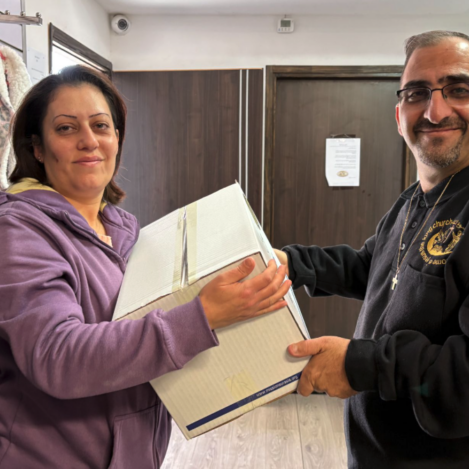 A man smiling while handing a large box of relief groceries to a woman in Nazareth.